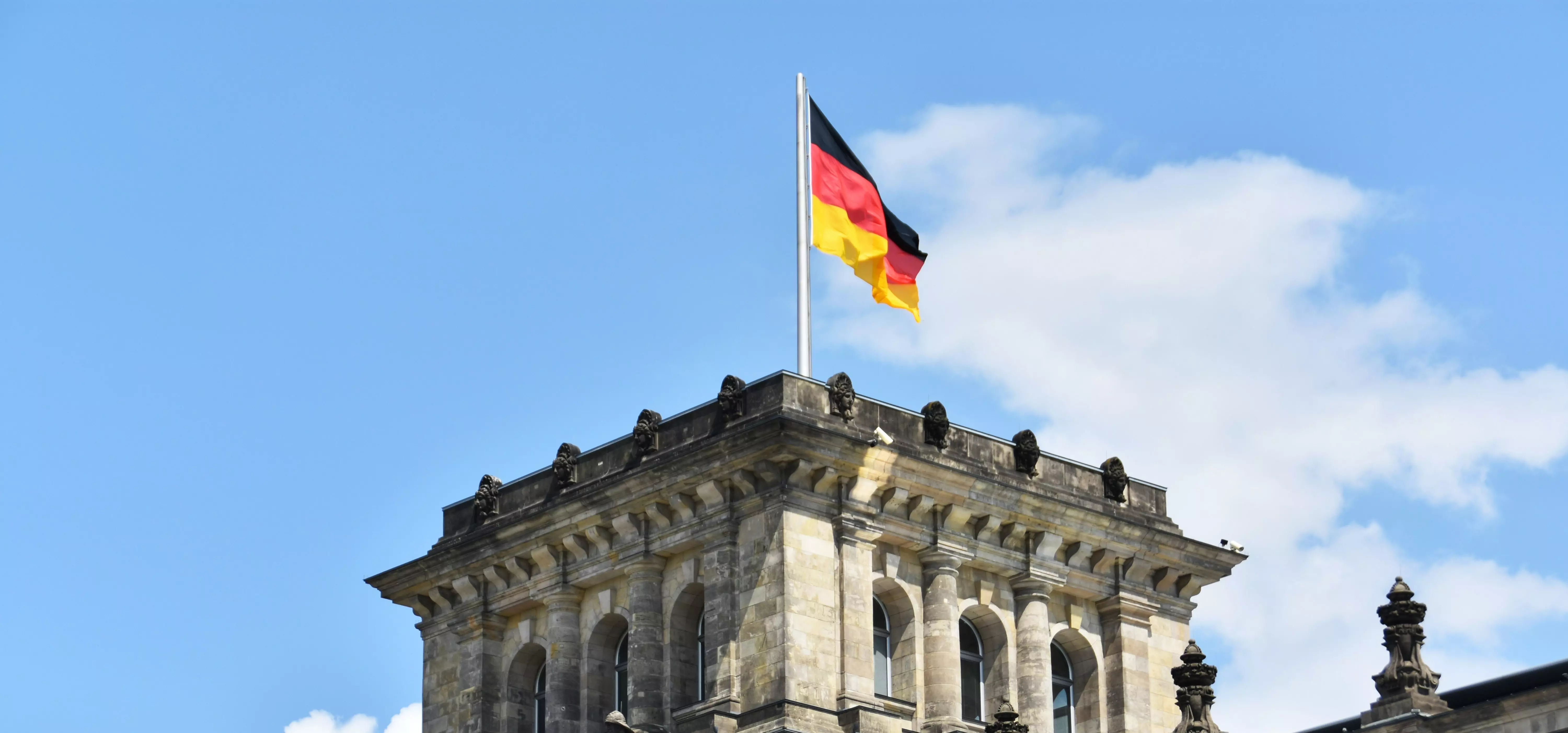 Deutsche Flagge über Rathaus vor blauem Himmel mit Wolken