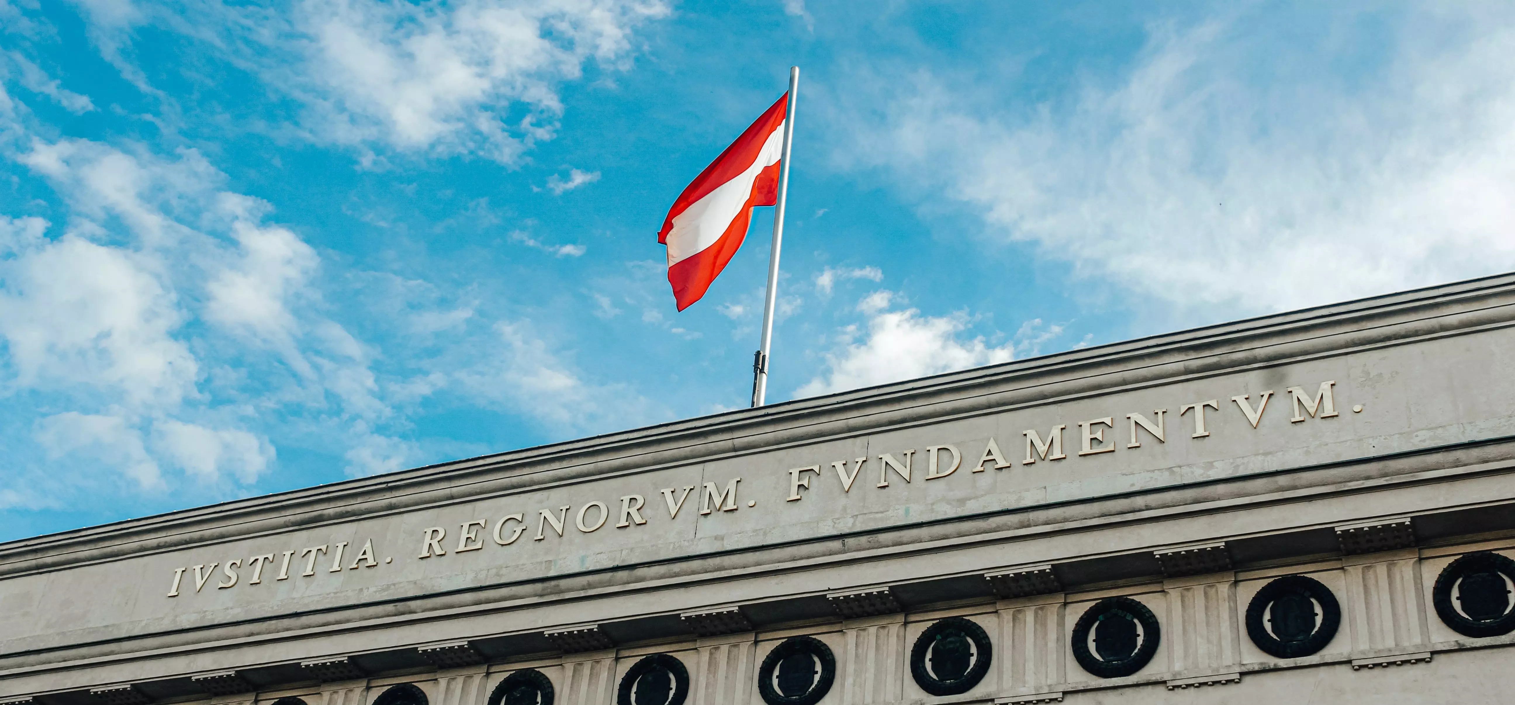 Österreichische Flagge über Parlament vor blauen Himmel mit Wolken